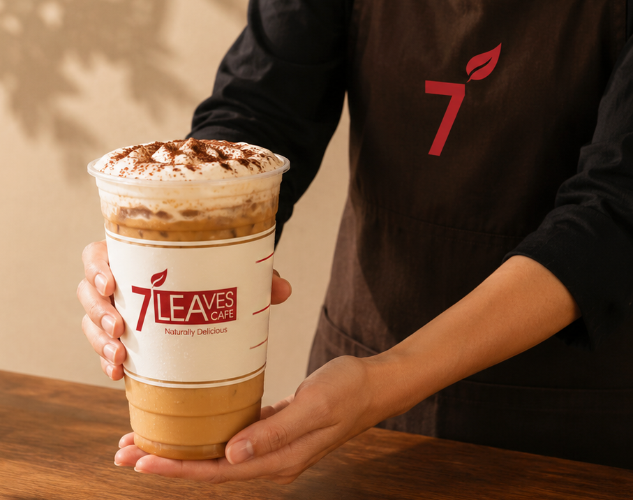 7 Leaves Cafe iced drink held in front of a barista apron